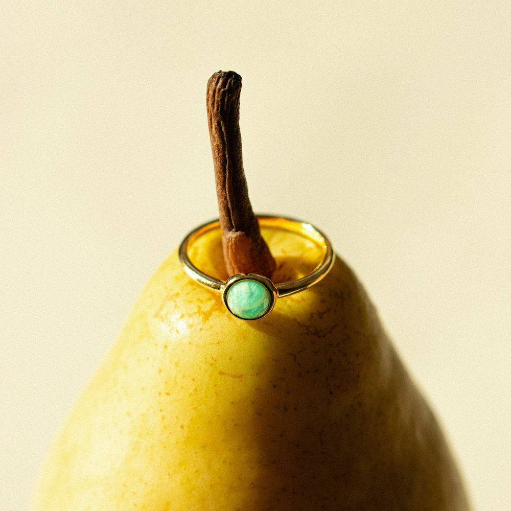 a gold ring with a turquoise stone sits on top of a pear