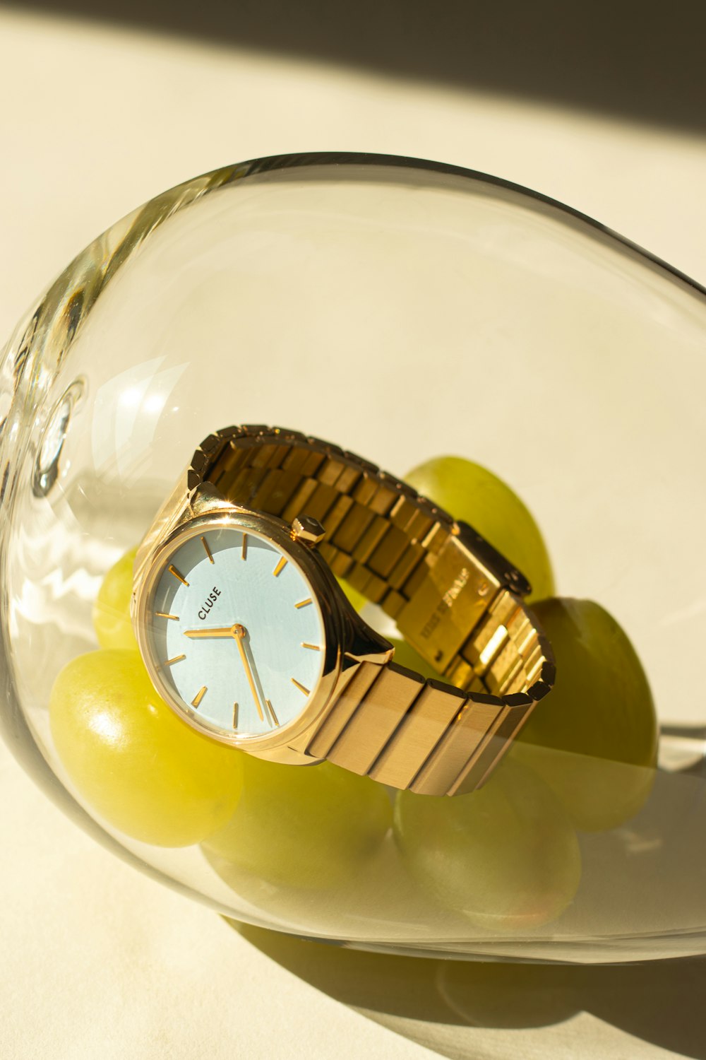 a watch and some grapes in a glass bowl