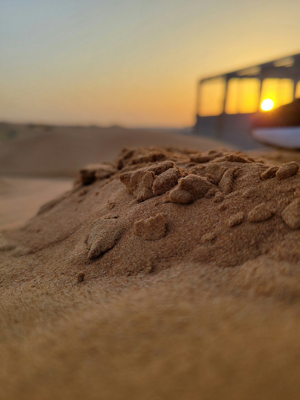 a close up of sand with a bus in the background