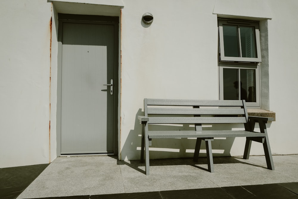 a wooden bench sitting in front of a white building