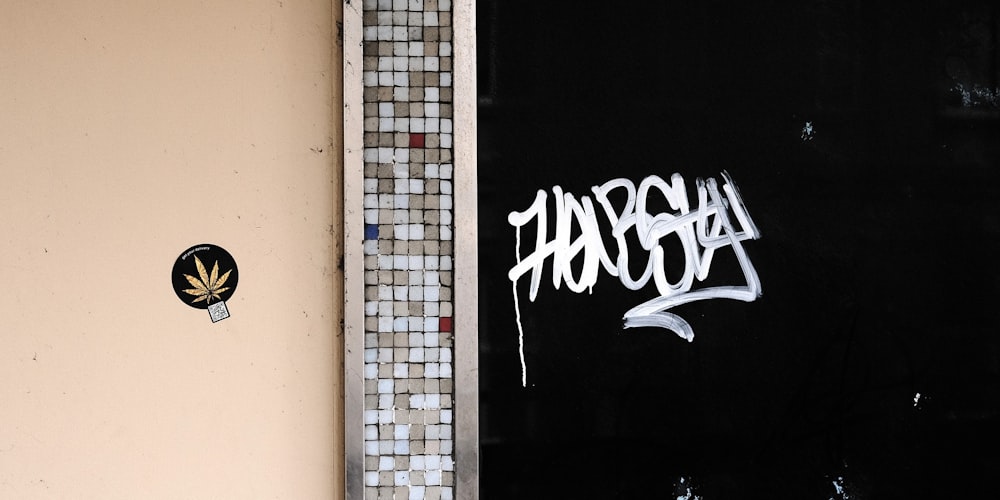 a door with graffiti on it next to a tiled wall