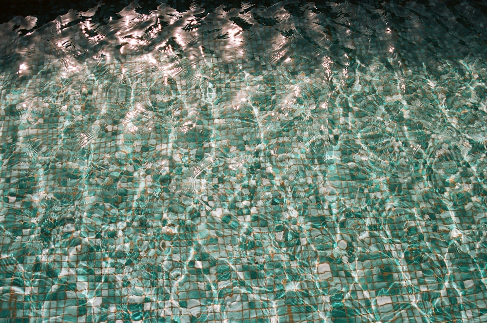 a swimming pool with clear water and green tiles