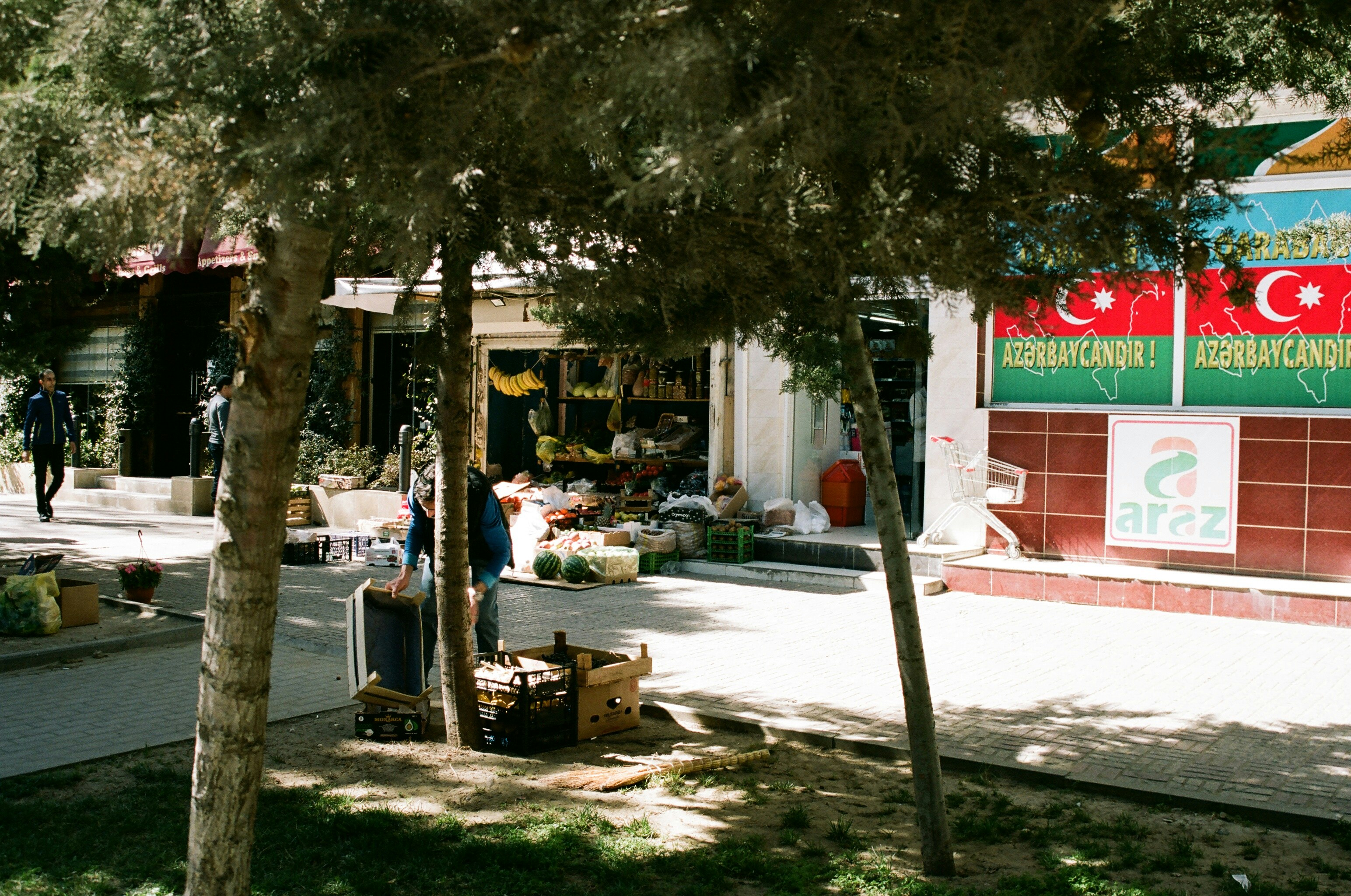 a man standing in front of a store next to a tree