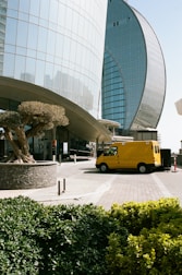 a yellow bus parked in front of a tall building