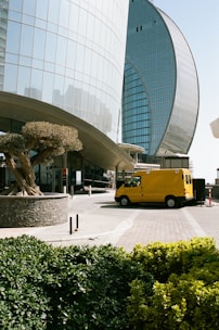 a yellow bus parked in front of a tall building
