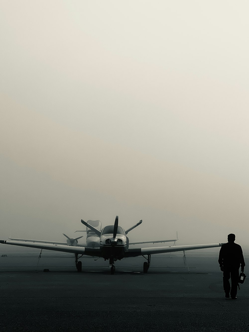 a man walking towards an airplane on a foggy day