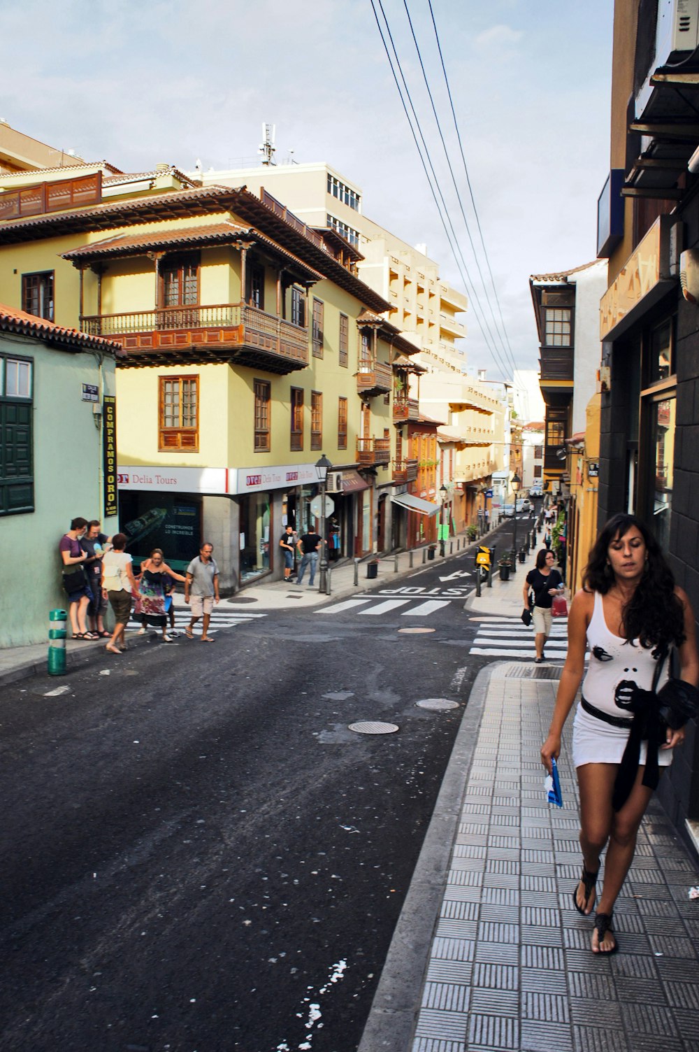 a woman walking down a street next to tall buildings