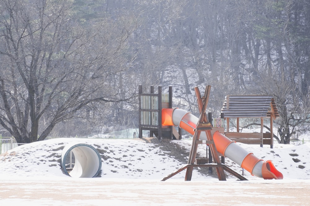 a playground in the snow with orange and white pipes