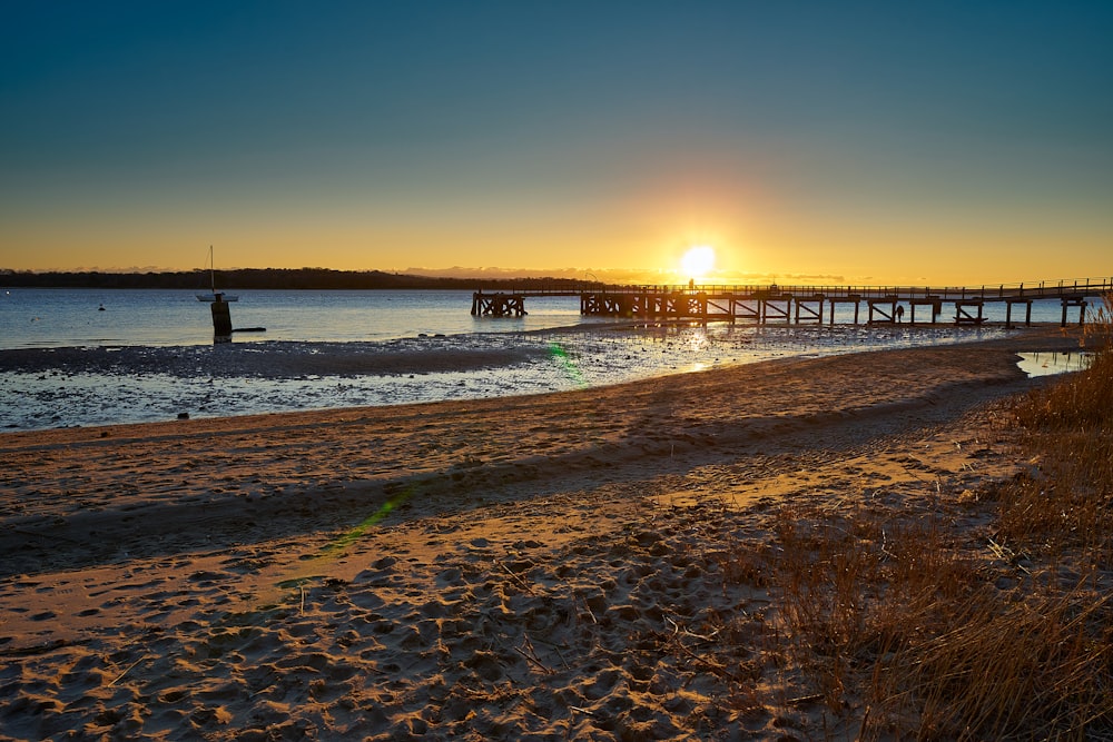 the sun is setting over the water at the beach