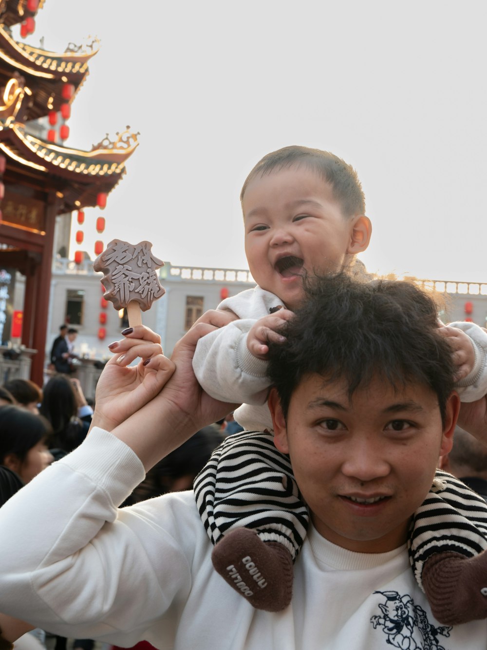 a man holding a baby on his shoulders