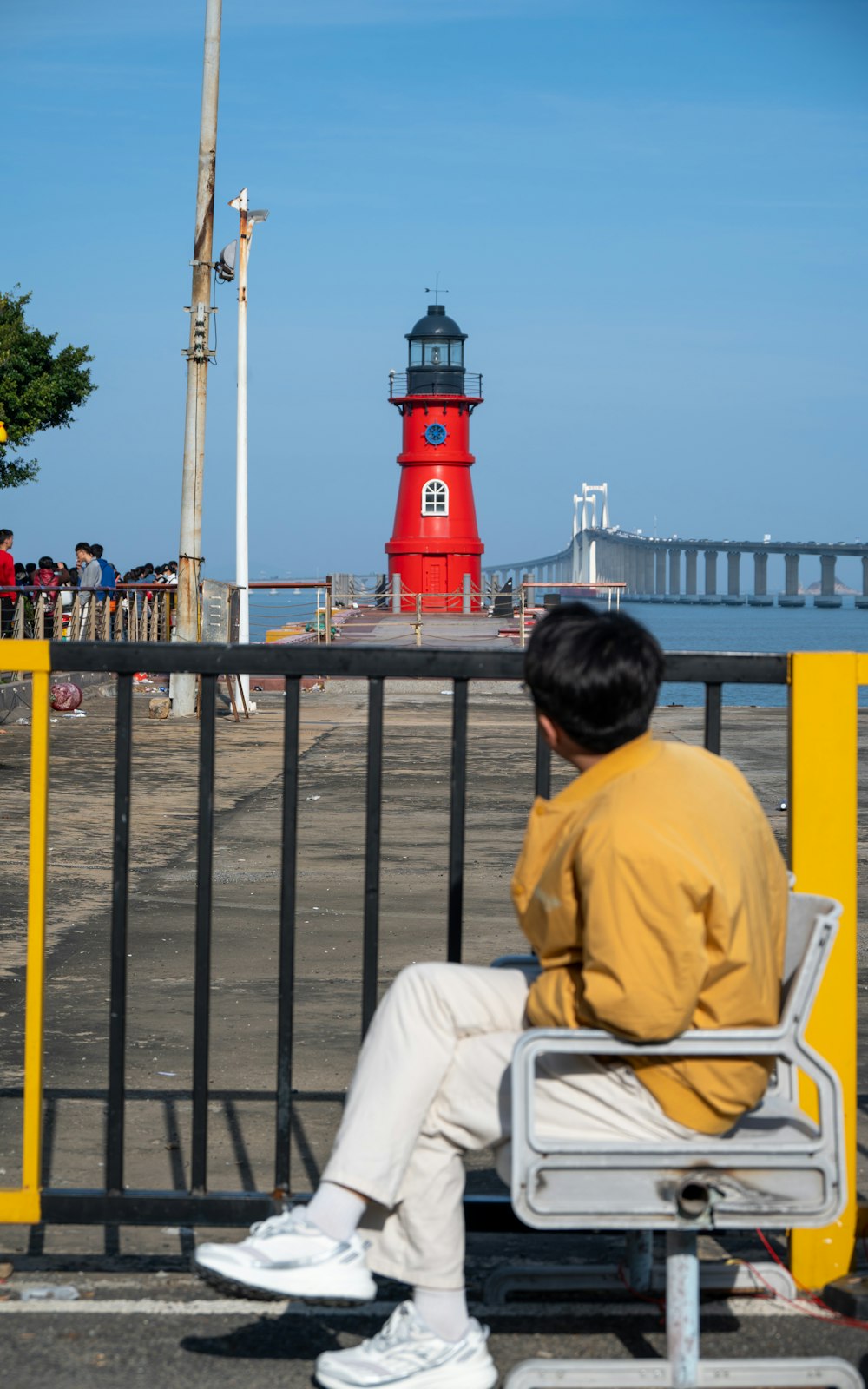 a man sitting on a bench next to a red light house