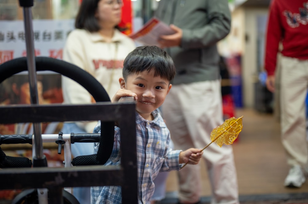 a young boy holding a yellow fan in his hand