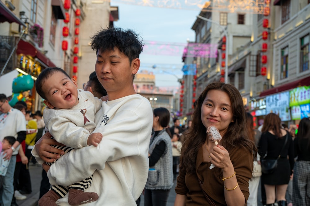 a man holding a baby in a crowded street