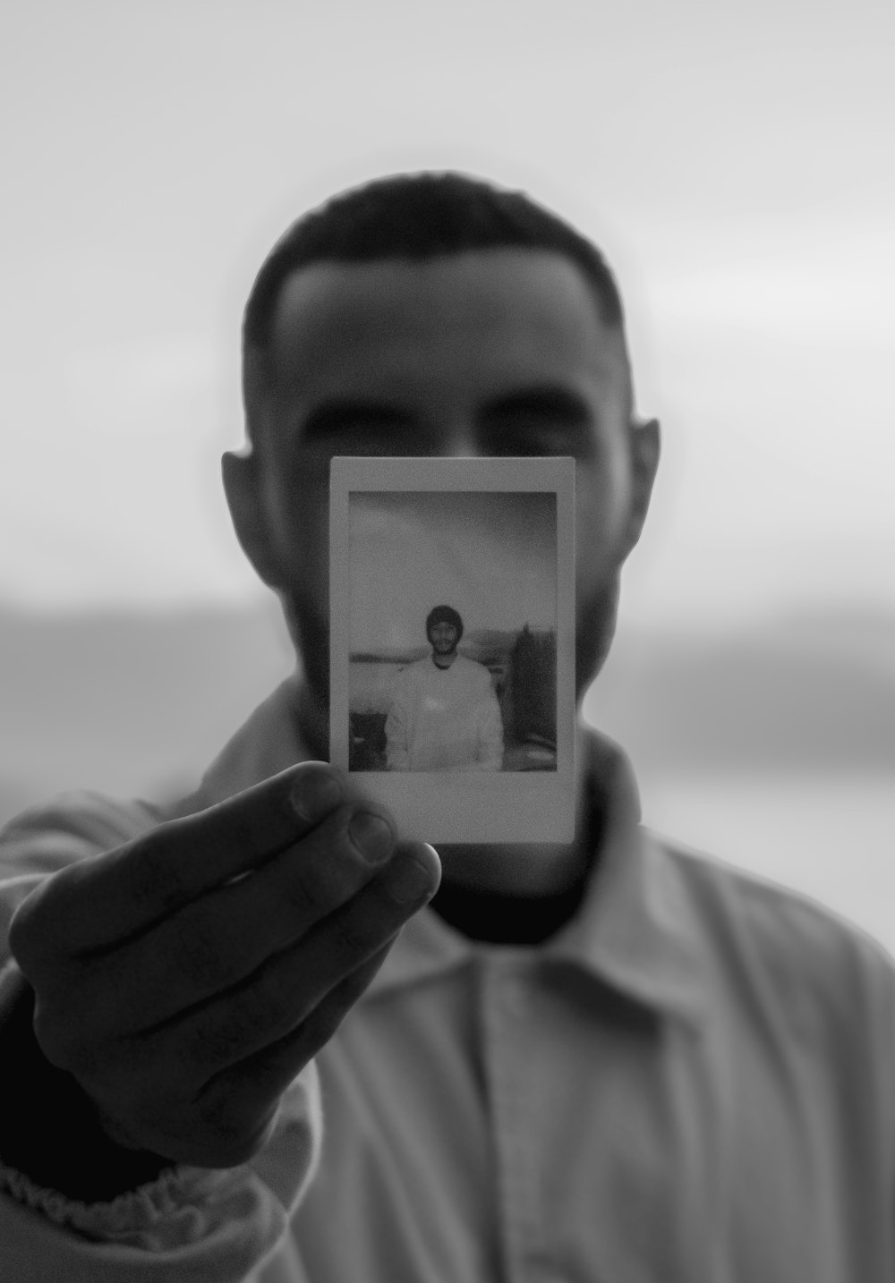 a man holding up a polaroid photo of himself