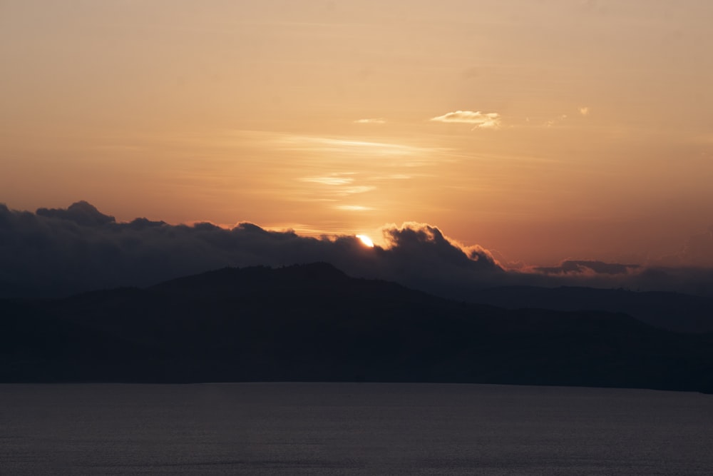 the sun is setting over a mountain range