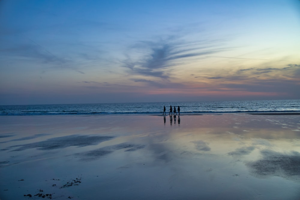 a group of people standing on top of a beach