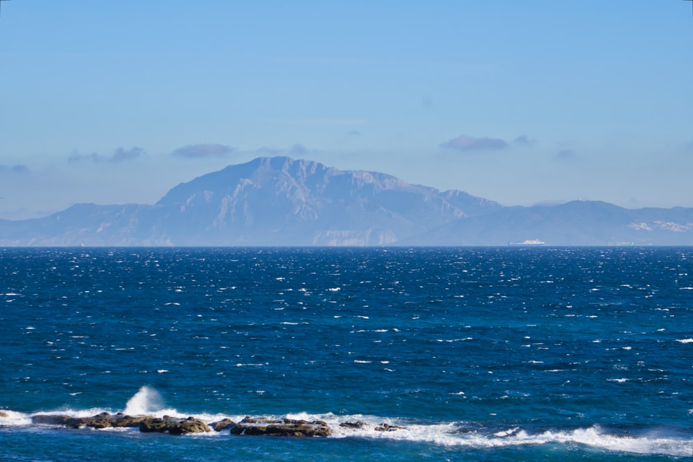 a large body of water with a mountain in the background