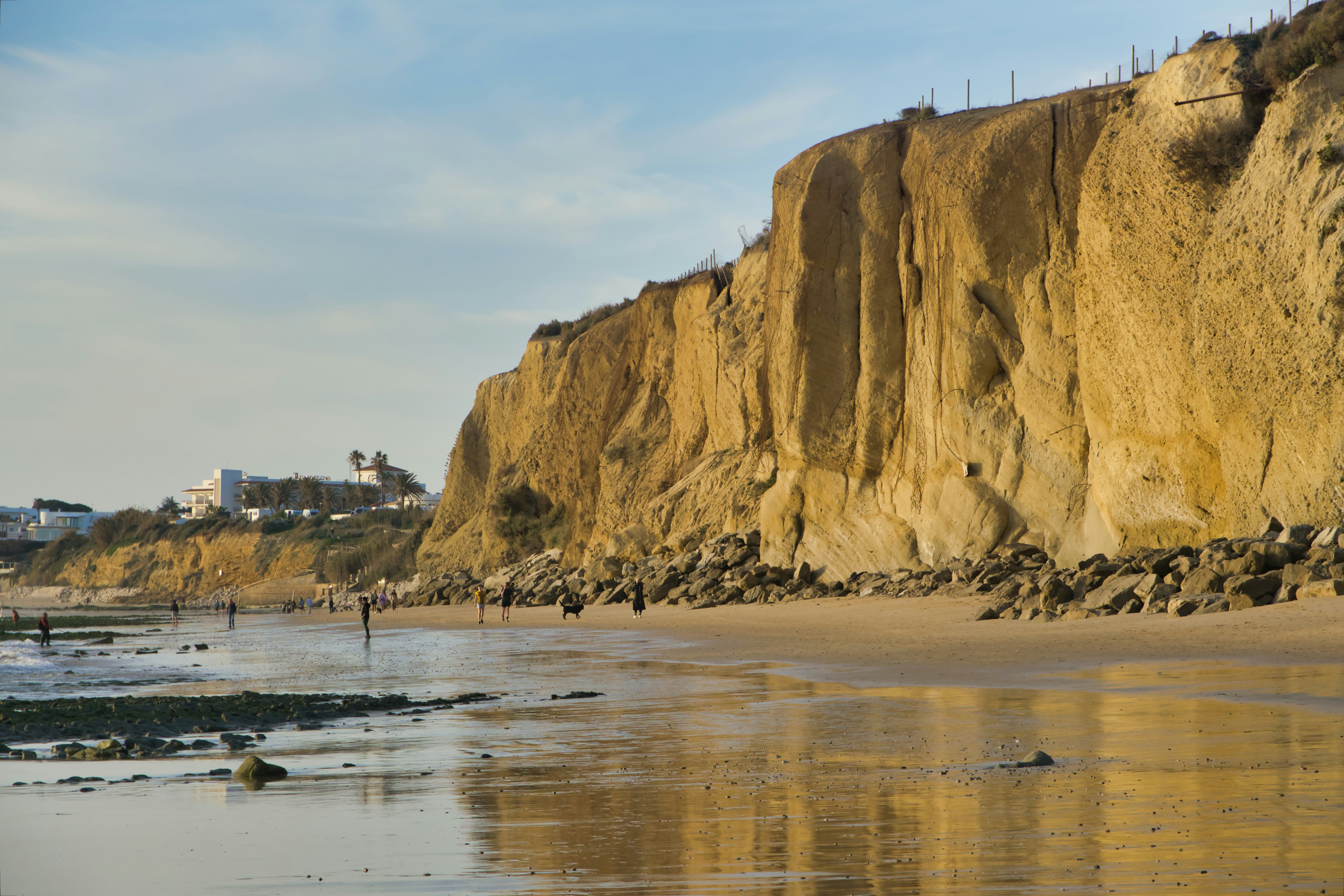 a sandy beach next to a cliff on a sunny day
