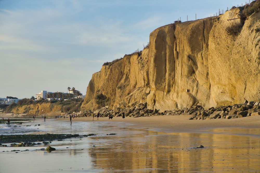 a sandy beach next to a cliff on a sunny day