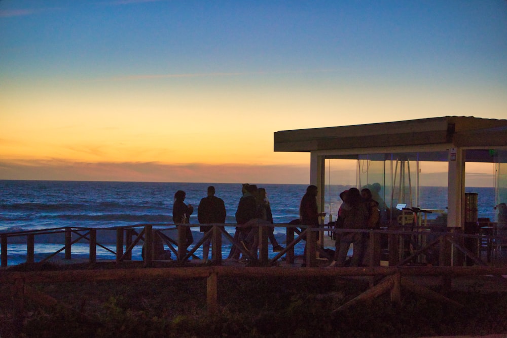 a group of people standing on top of a pier next to the ocean