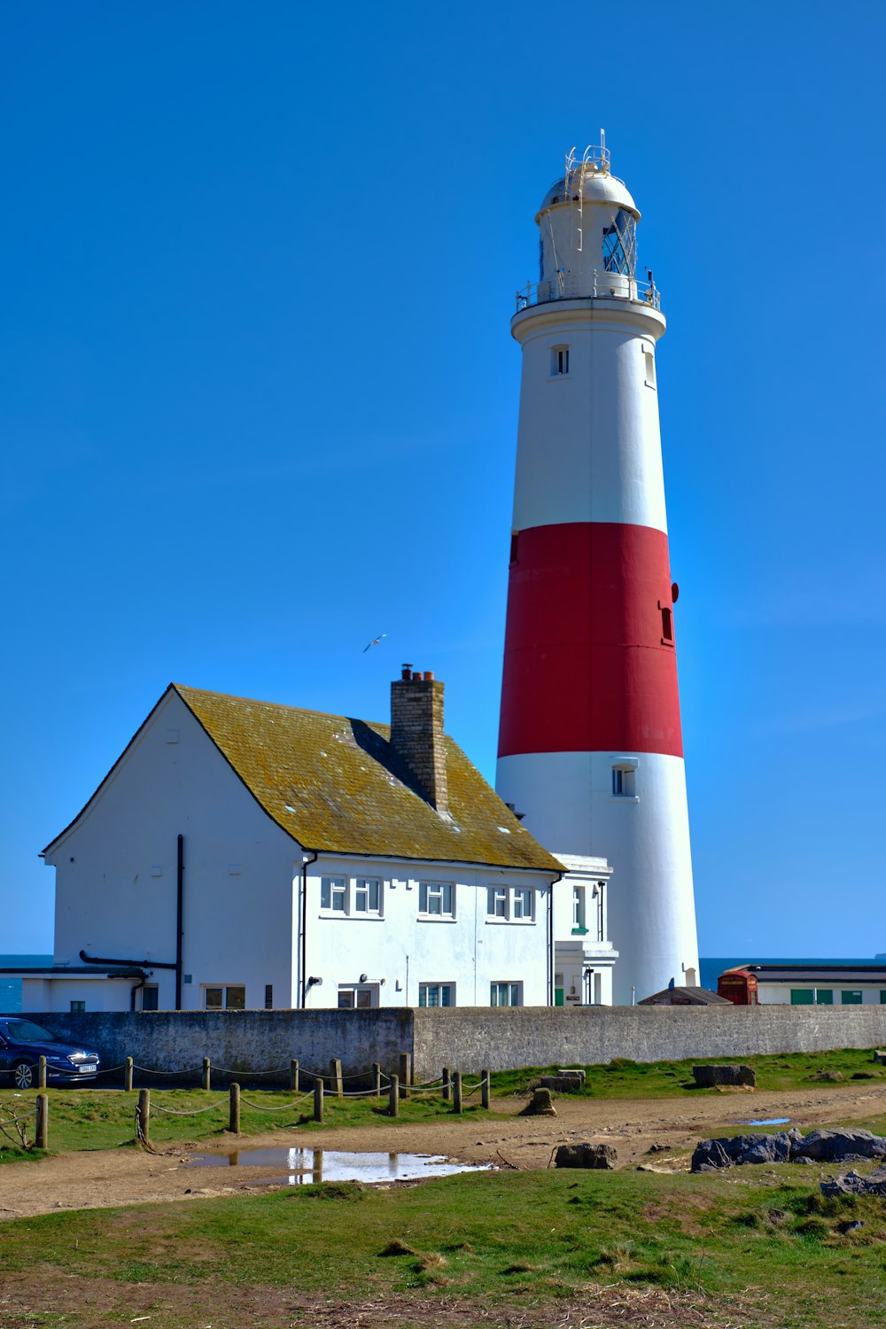 a red and white lighthouse next to a white building