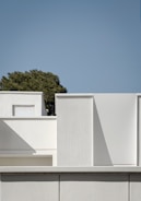 a white building with a tree in the background