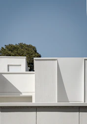 a white building with a tree in the background