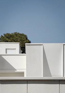 a white building with a tree in the background
