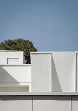 a white building with a tree in the background