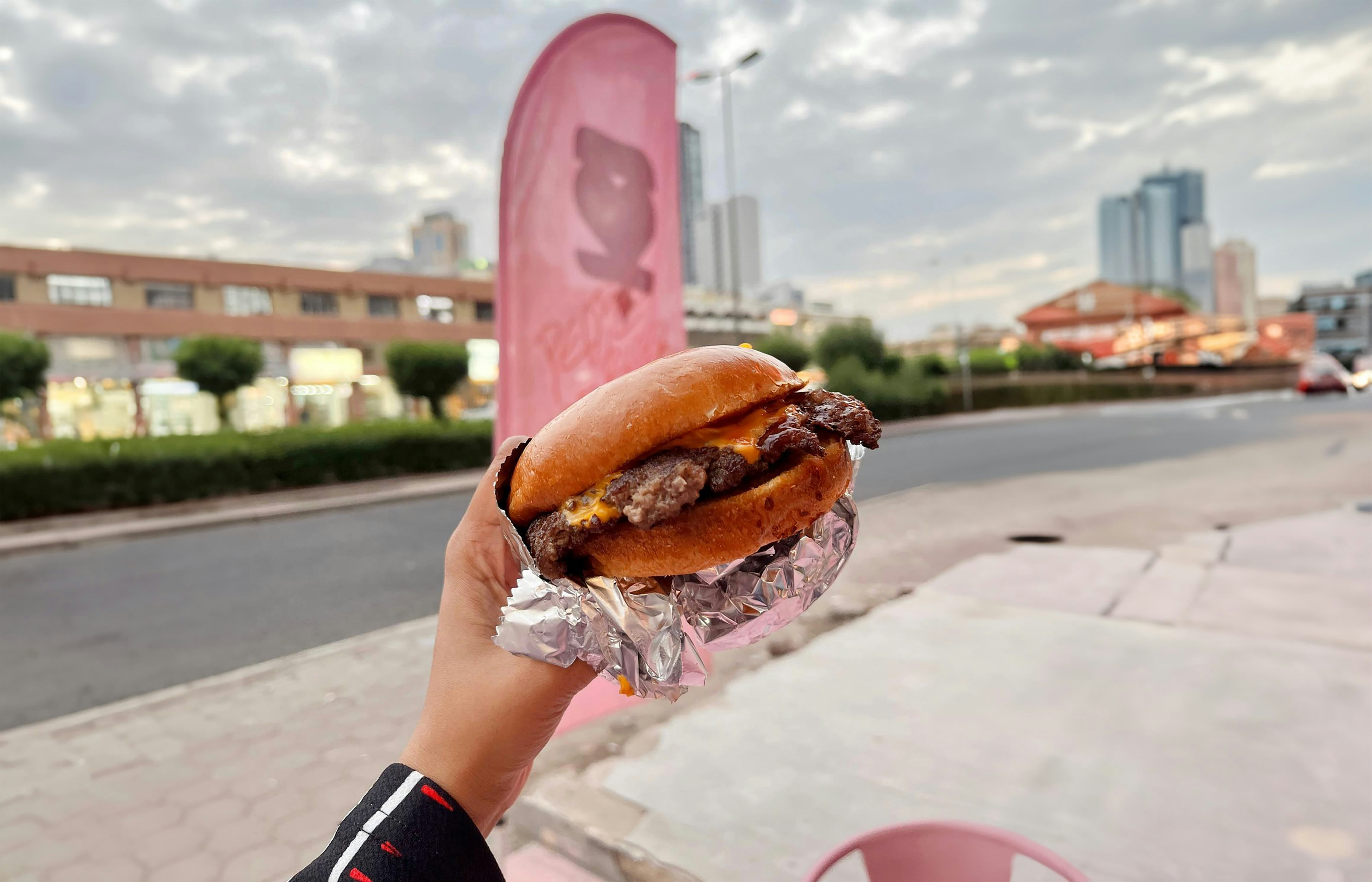 a person holding a large hamburger in their hand