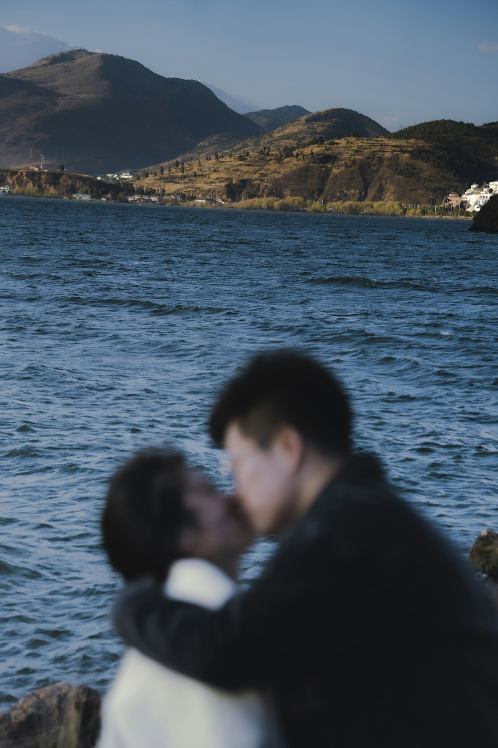 a man and a woman kissing by a body of water