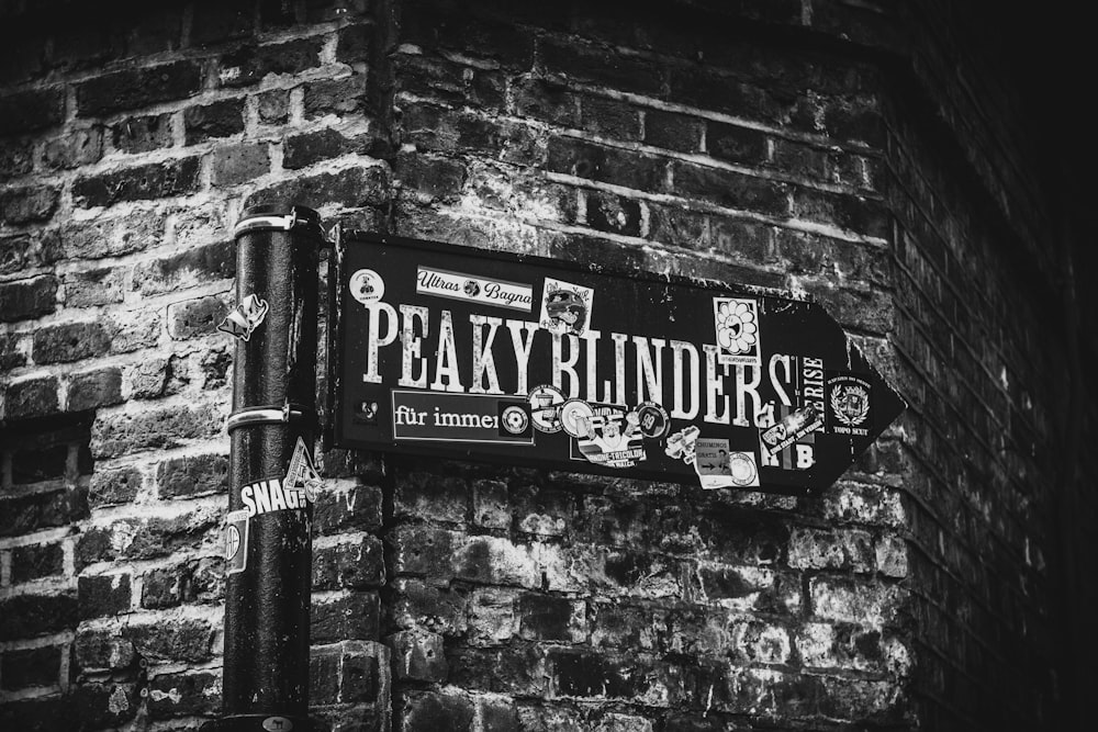 a black and white photo of a sign on a brick wall