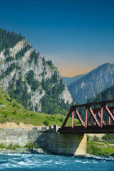 a bridge over a river with mountains in the background