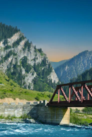 a bridge over a river with mountains in the background
