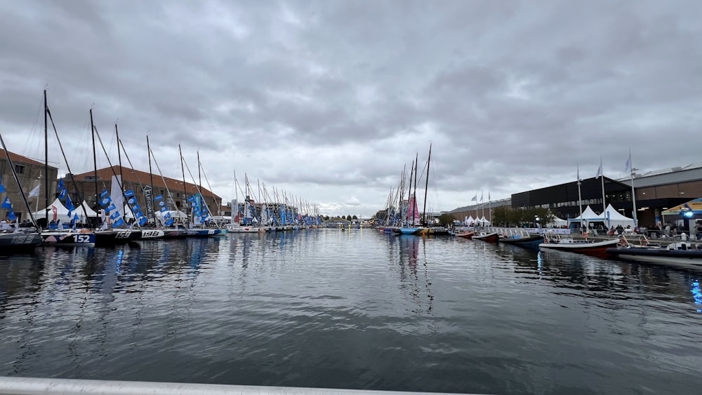 a harbor filled with lots of sailboats under a cloudy sky