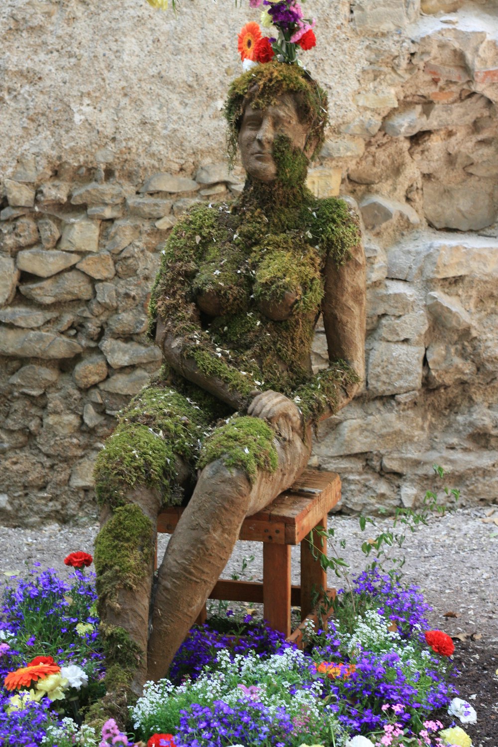 a statue of a woman sitting on top of a wooden bench