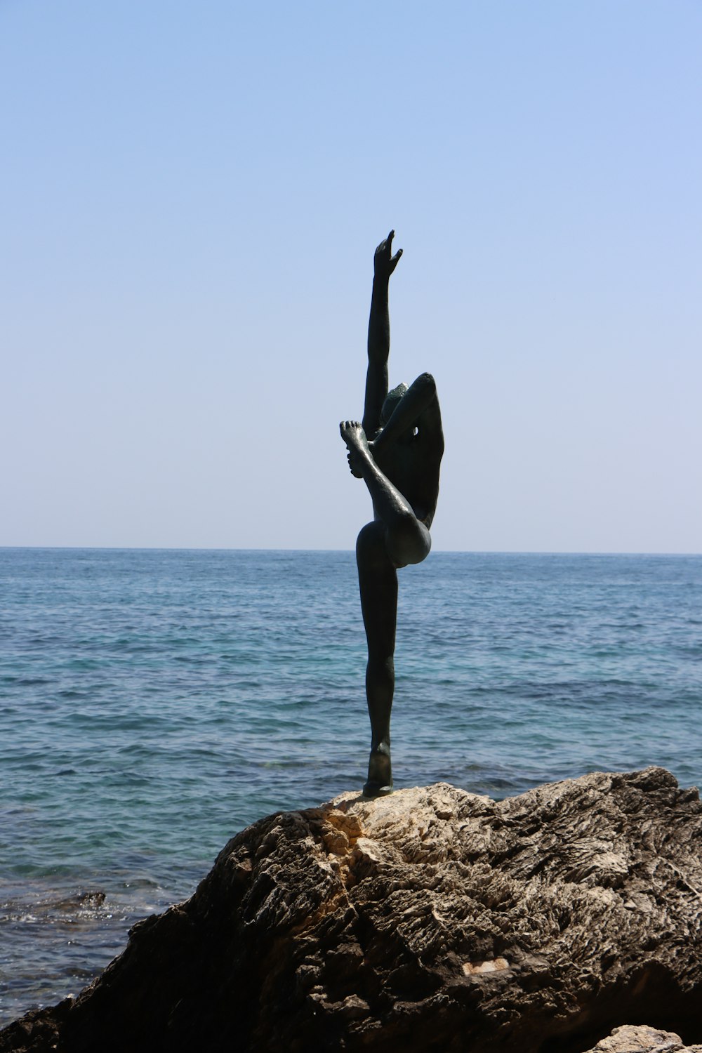 a person doing a handstand on a rock near the ocean
