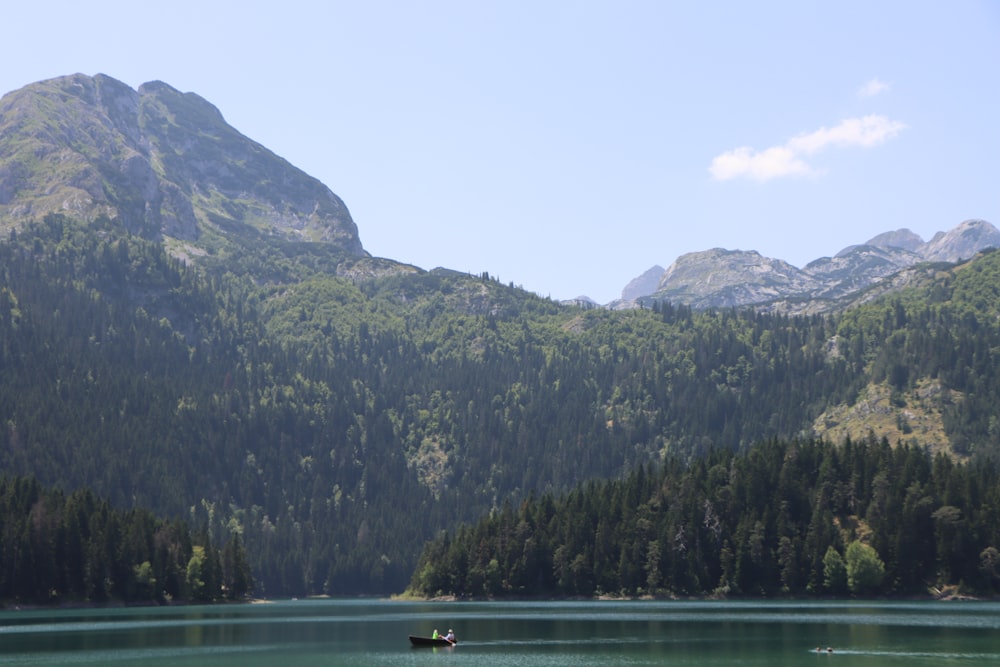 um barco flutuando no topo de um lago cercado por montanhas