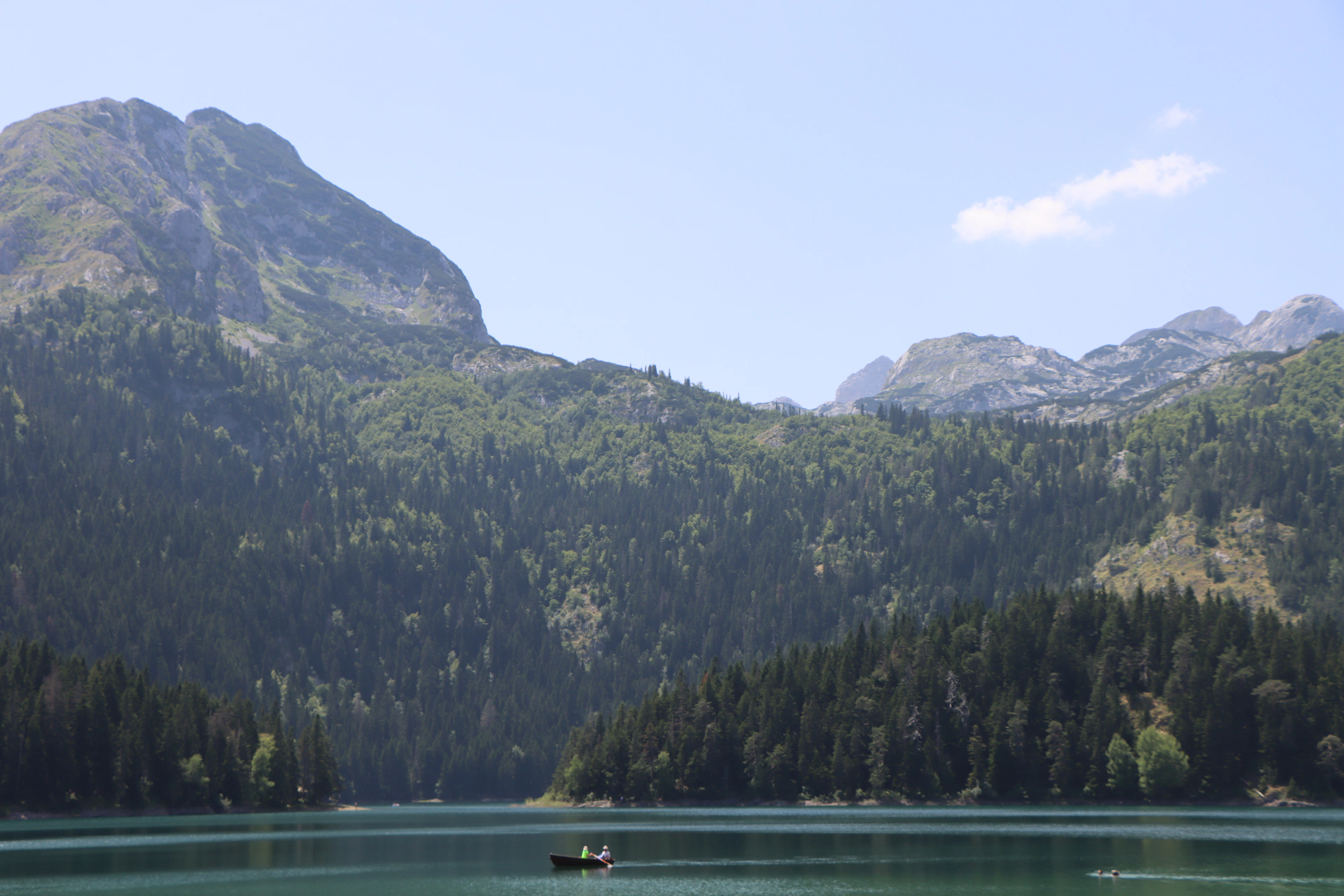 A boat on the Black Lake below forested slopes and rocky peaks, Durmitor National Park, Montenegro