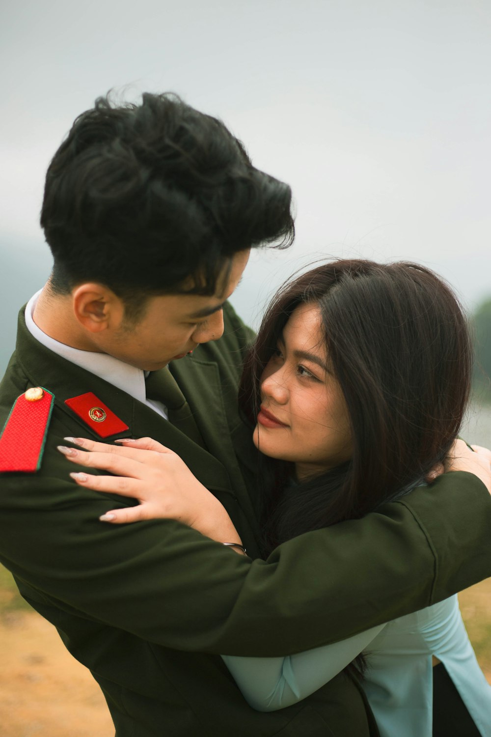 a man in a military uniform hugging a woman