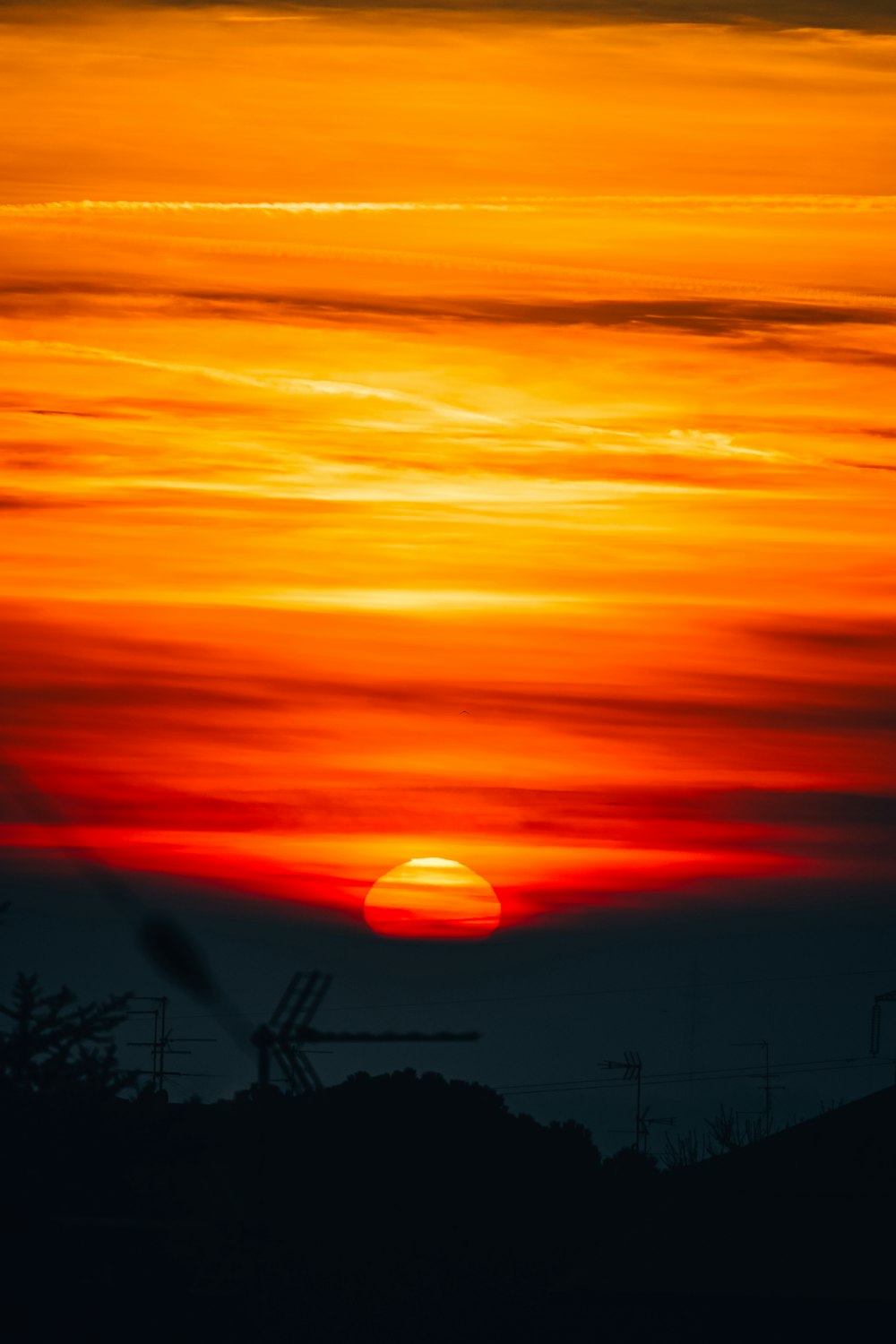 the sun is setting in the sky over a hill