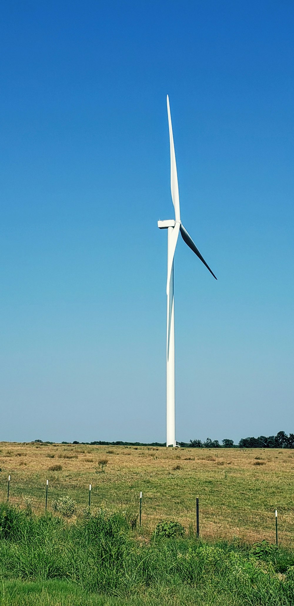 a large white wind turbine in a grassy field