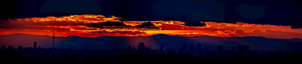 Die Sonne geht über einer Stadt mit Bergen im Hintergrund unter