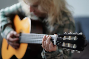 a woman playing a guitar while sitting on a couch
