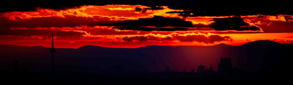 Die Sonne geht über einer Stadt mit Bergen im Hintergrund unter