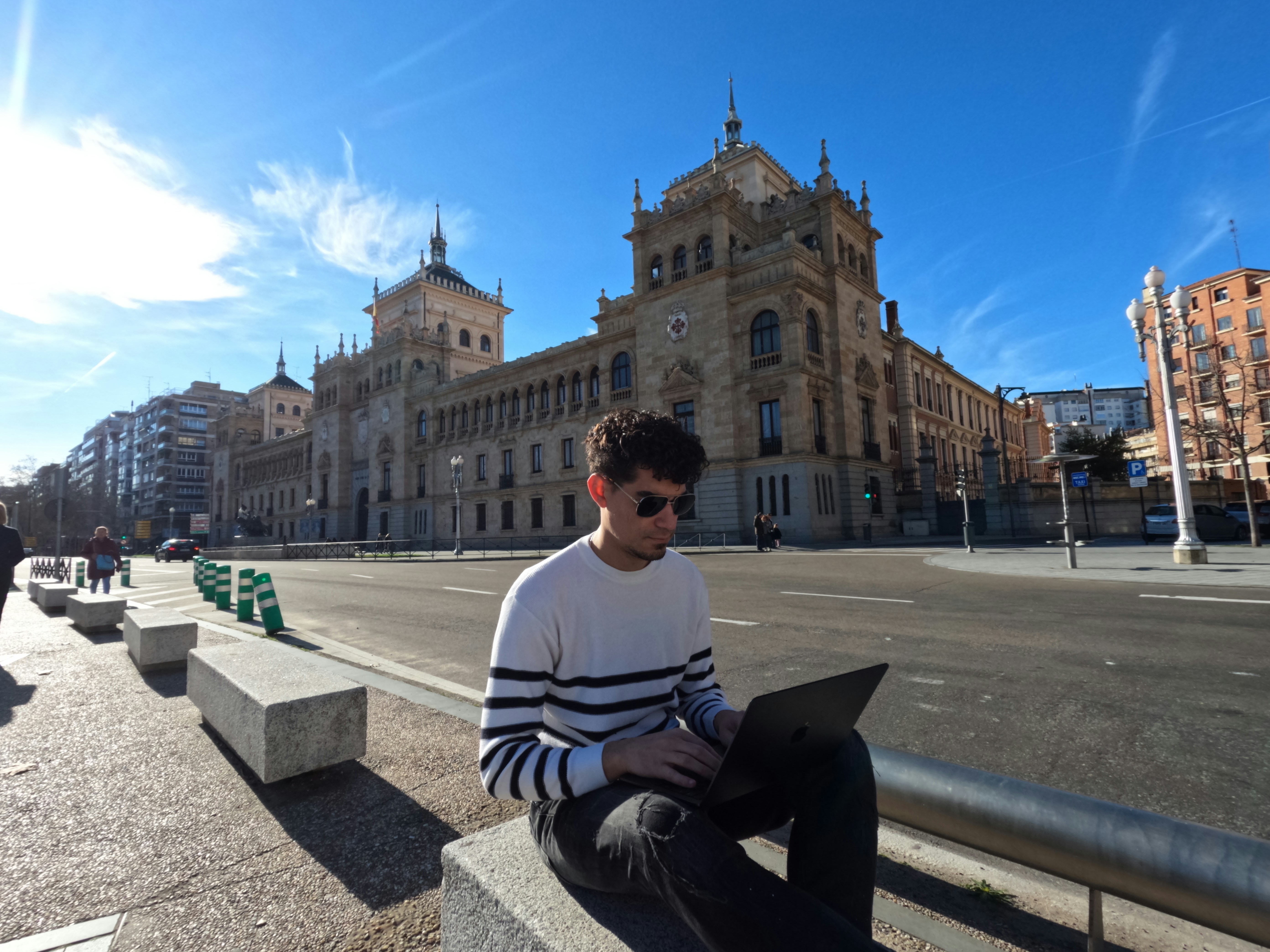 a man sitting on a bench using a laptop computer, Trabajo Remoto