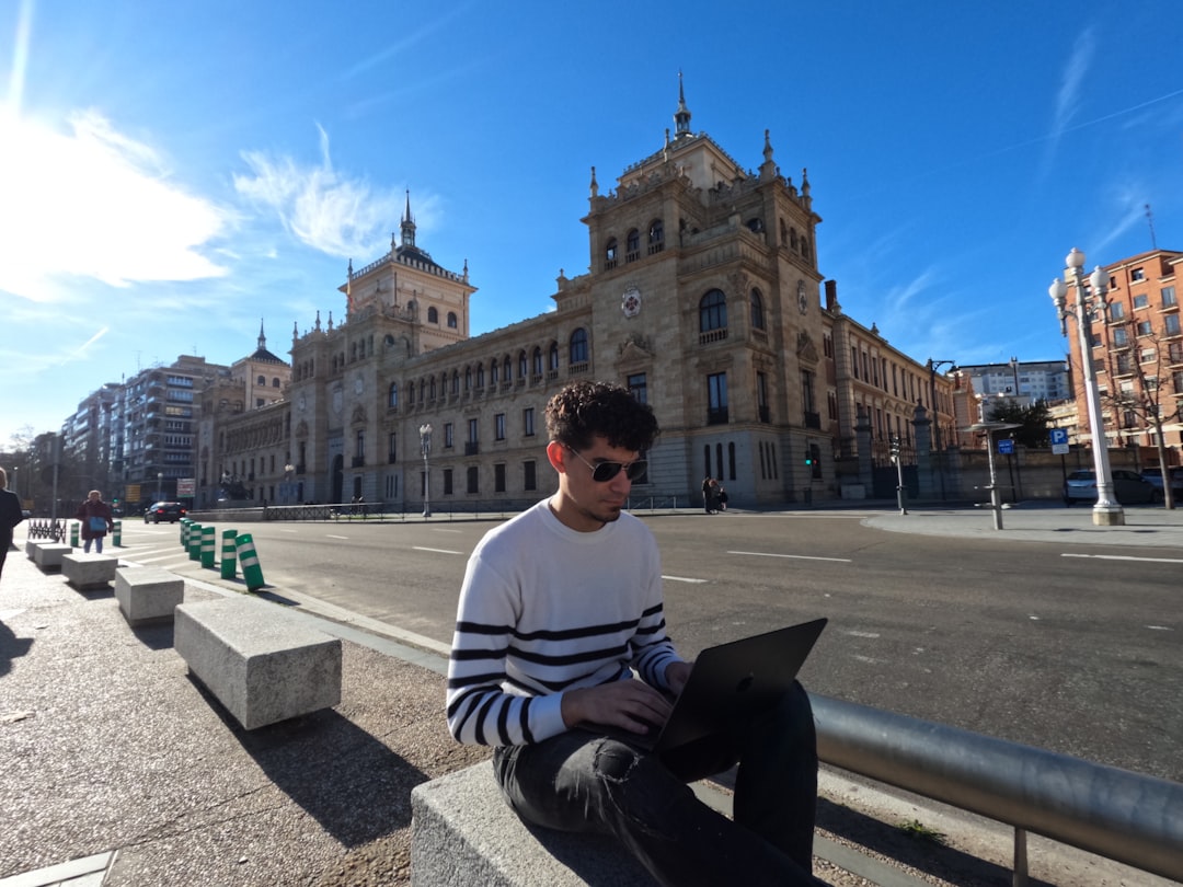 a man sitting on a bench using a laptop computer, Trabajo Remoto