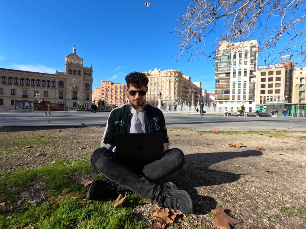 a man sitting on the ground with a laptop