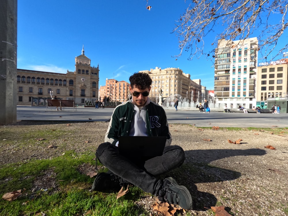 a man sitting on the ground using a laptop