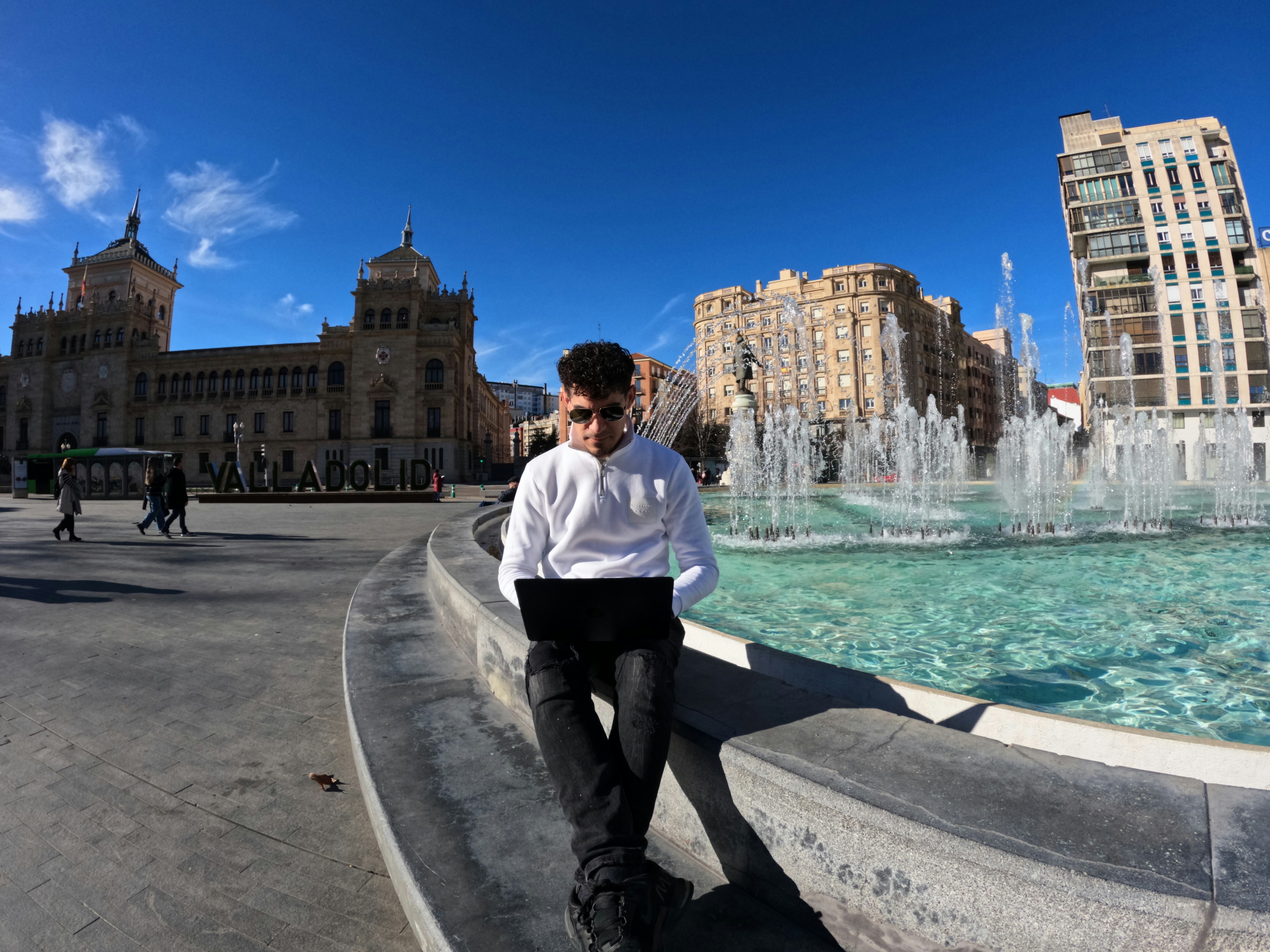 a man sitting on the edge of a fountain, Trabajo Remoto